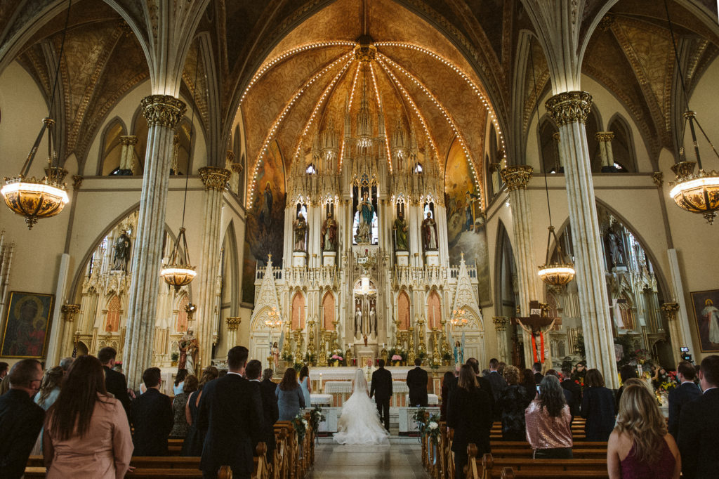 Bride and groom stand in front of guests in huge beautiful church