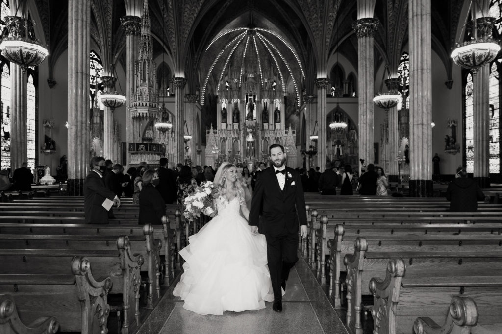 Bride and groom smiling as they walk down the church aisle
