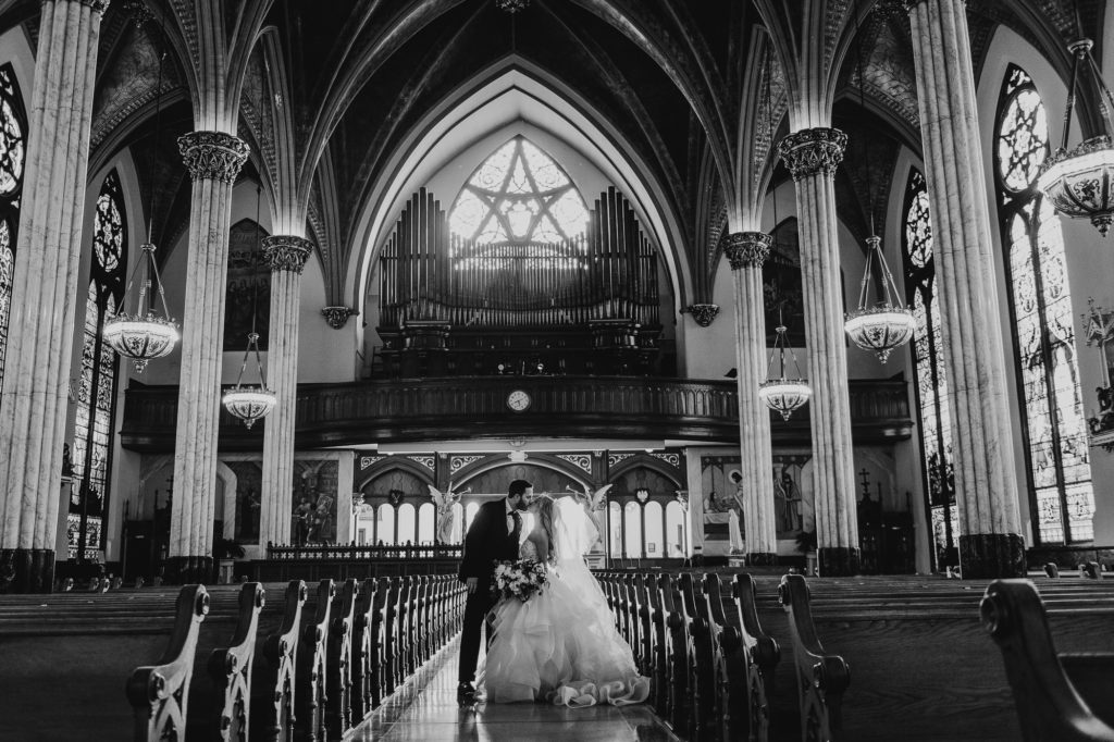Bride and groom kiss with the empty church behind them