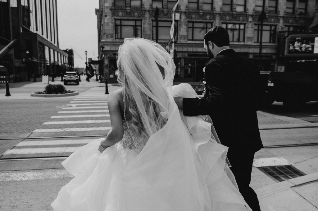 Bride and groom running across city street